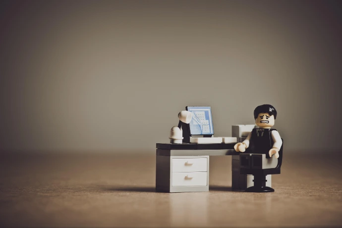 legopopje dat bezorgd kijkt aan zijn lego bureau en lego computer